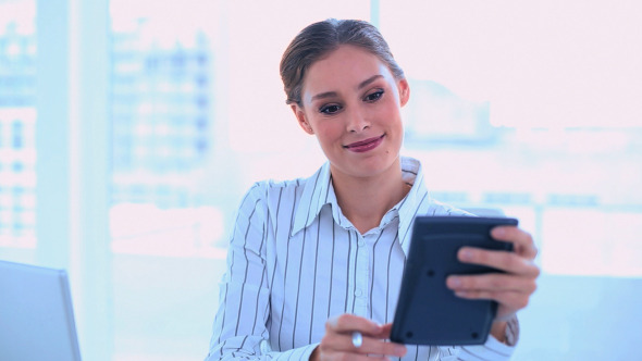 Concentrated Businesswoman Using A Calculator
