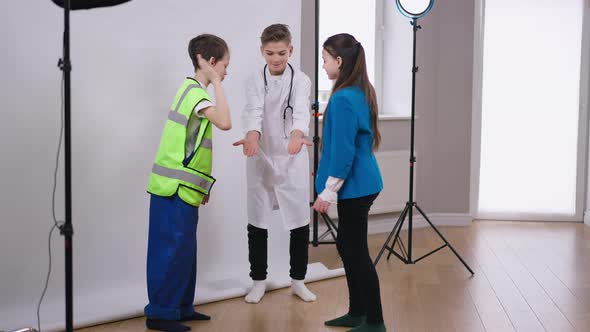Wide Shot Portrait of Positive Smiling Handsome Teenage Boy in Medical Gown Gesturing Low Five with alt