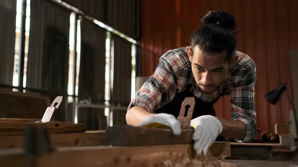 Young Asian man carpenters are using spokeshave to decorate the woodwork. alt
