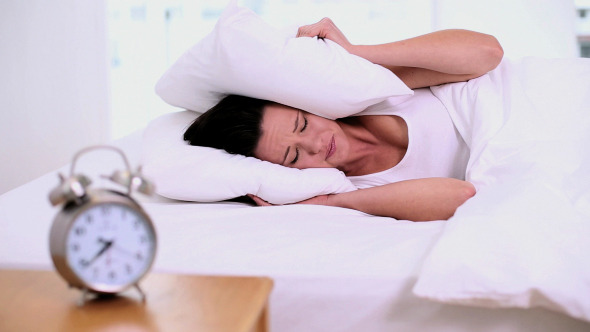 Exhausted Woman Lying On Her Bed Covering Her Ears