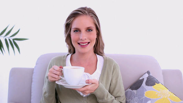 Content Woman Drinking From Cup Sitting On Couch