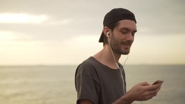 Closeup Smiling Caucasian Bearded Man with Cap on Backward Listening Music Using Headphones Early in alt