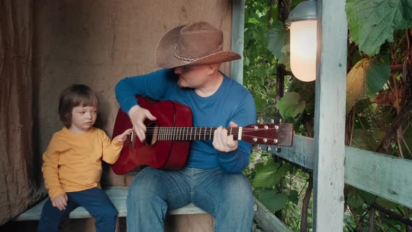 Dad Cowboy Plays an Acoustic Guitar for His Small Child
