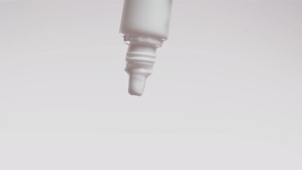 Closeup bottle of medicine for ears or eyes from which drop is dripping, white background in studio. alt