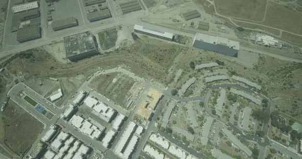 Helicopter aerial moving slowly toward red and white turboprop plane flying over mountains, cloudy d