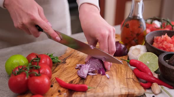 Woman Chopping Red Onion on Wooden Board at Domestic Kitchen alt