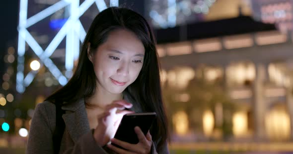 Businesswoman use of mobile phone in city in the evening alt