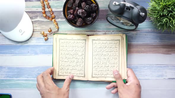 Muslim Man Hand Turning Pages of Holly Book of Quran Top View alt