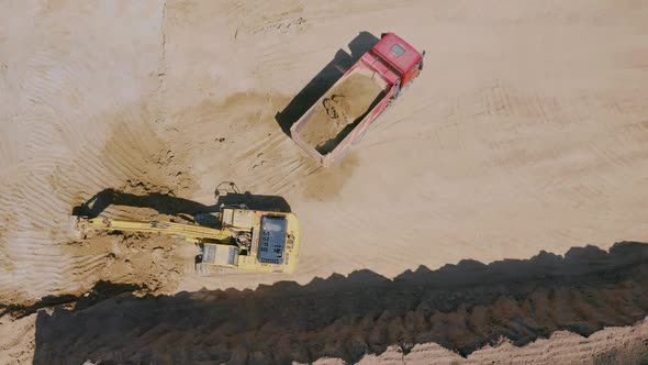 Excavator Loads Sand Into a Dump Truck on a Sand Pit alt