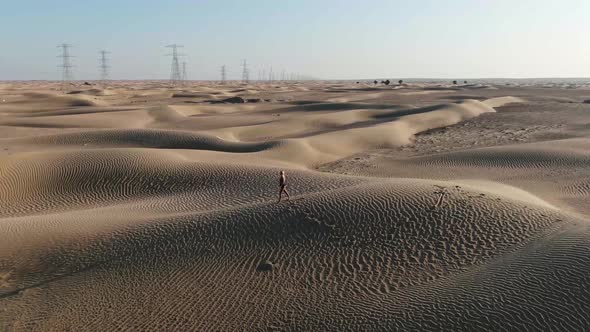 Landscape View on the Great Sandy Desert in UAE with a Woman Walking on Sand alt