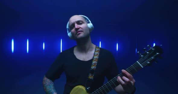Happy Male Musician Playing Guitar Against Bright Lights alt