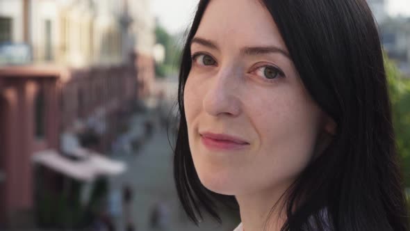Adult Brunette Woman Turns Head and Looks at Camera in City alt