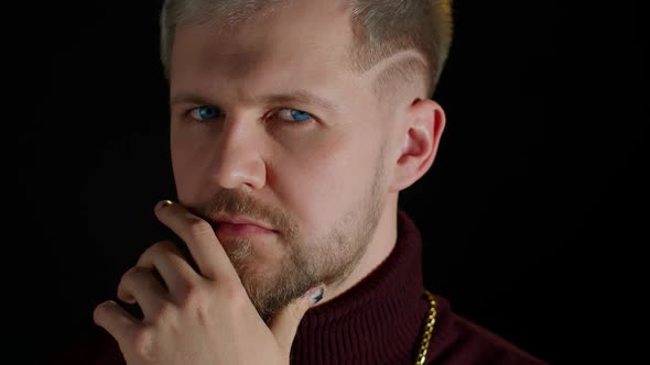 Confident Bearded Man in Stylish Clothing Sensually Touching Lips with Finger on Black Background alt