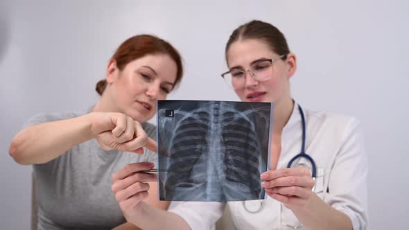 The Doctor Consults a Caucasian Woman and Comments on the Xray of the Lungs alt