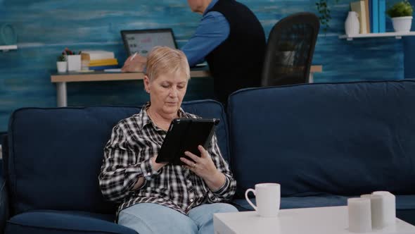 Middle Aged Old Woman Relaxing Holding Tablet Reading e Book alt