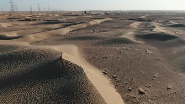 Young Woman is Sitting on Top of a Sand Dune and Throwing Sand Sunset alt
