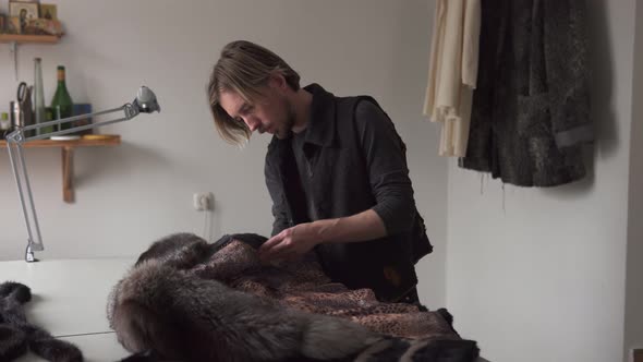Man Tailor Touching Fur for Sewing Coat in Furrier Workshop