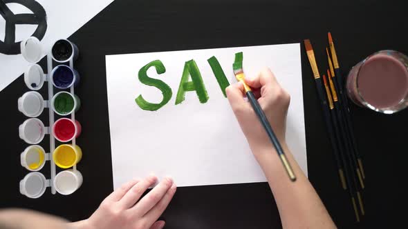 Human Hands Draw Poster with Paints and Brush on Blank Sheet with Call to Save the Planet