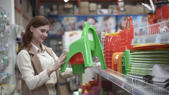 Baby Care, Young Happy Mother Buys a Chamber-pot for Her Child in a Shopping Center While Shopping alt