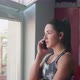 Young Woman in Sport Outfit is Standing Near the Window Talking on the Phone and Drinks Multivitamin - VideoHive Item for Sale
