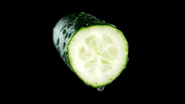 Half of Tasty Broken Cucumber with Water Drops on Black alt