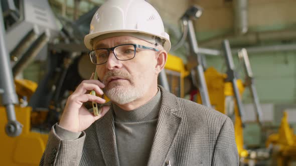 Senior Engineer Walking in Factory and Having Phone Talk alt