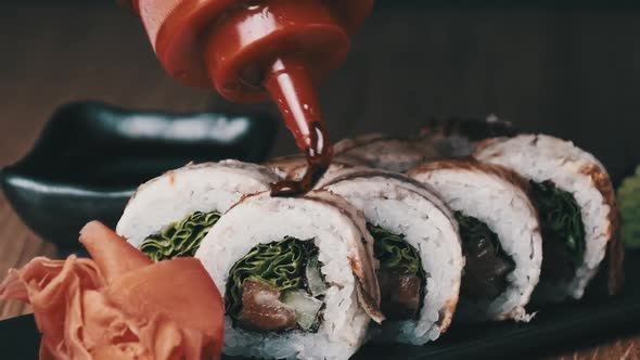 Appetizing Sushi is Poured with Sweet Sauce on a Wooden Table in Restaurant alt