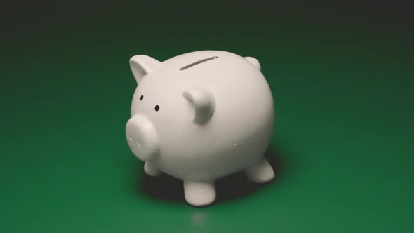 Female Hand Breaks Piggy Bank Moneybox with Hammer on Green Background