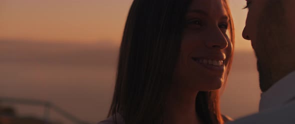 Close up of a young woman looking at her boyfriend with love, smiling, at sunset. Slow motion.  alt