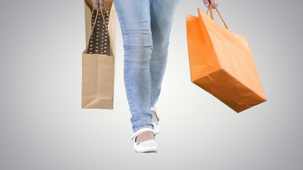 Little girl with shopping bags walking on gradient background. alt