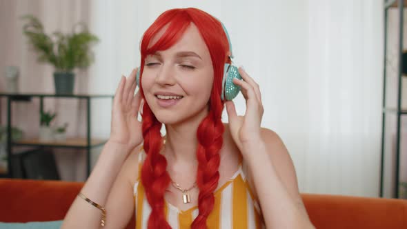 Happy Young Redhead Girl in Wireless Headphones Dancing Singing Listening Favorite Song at Home Room alt