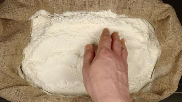 Human hand touching a wheat powder in a sac