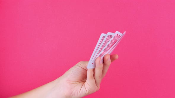 Five of a kind Poker Game cards in gambler hand falling money bills pink background alt