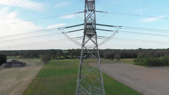 Tall steel lattice transmission tower pylon and power lines, rising aerial reveal alt