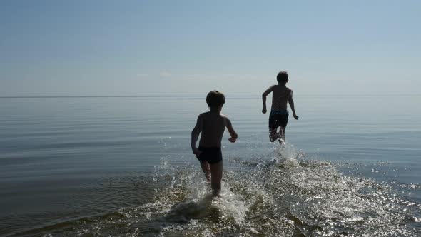 Happy Boys Running Into the Sea Water in Sunny Day