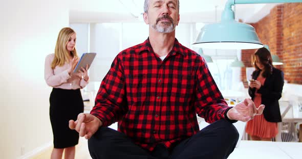 Male executive performing yoga while his executive standing in background alt