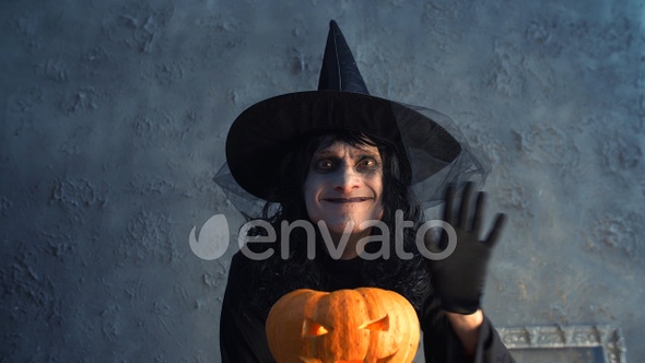funny scary Halloween witch holding a pumpkin