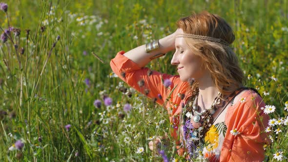 Portrait of Blonde Hippie Dancing in a Field with Flowers alt