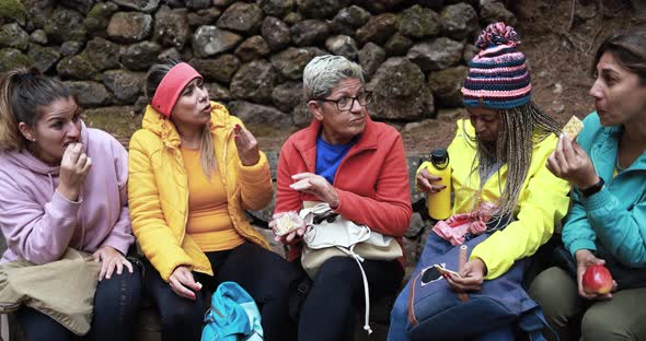 Multiracial women eating a snack during trekking day alt