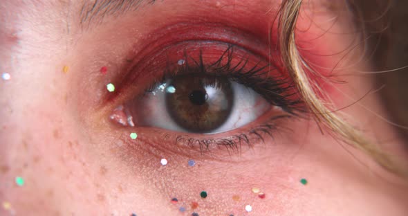 Close up of brown eyes blinking with glitter alt