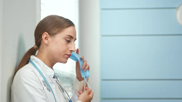 Tired Brunette With Long Hair In Ponytail Medical Nurse Takes Off Blue 