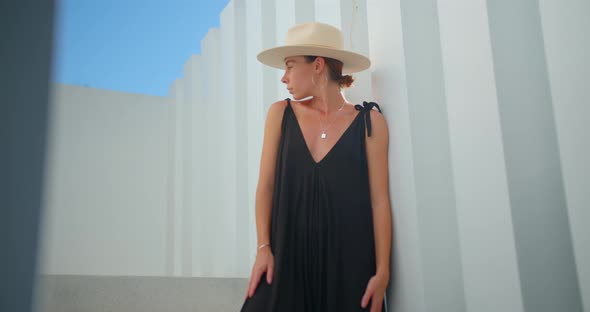 Woman Posing on the Stairs Stands Over White Background Black Dress and Hat alt