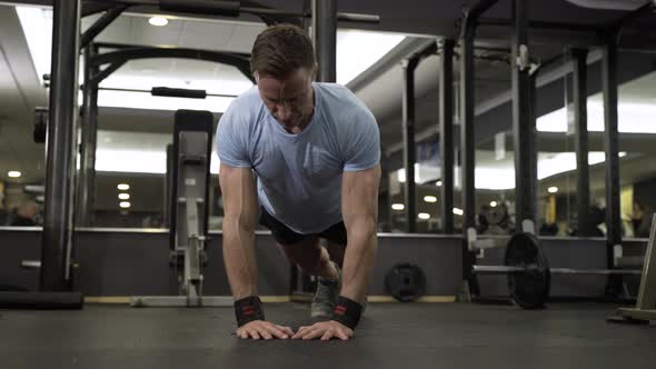 Image of an attractive man doing push-up at the gym. alt