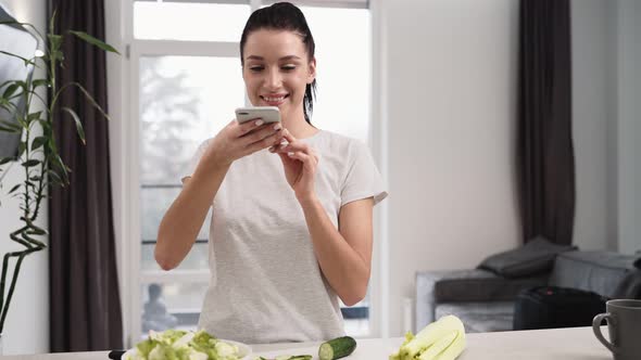 A beautiful woman using her mobile while taking photo of salad alt