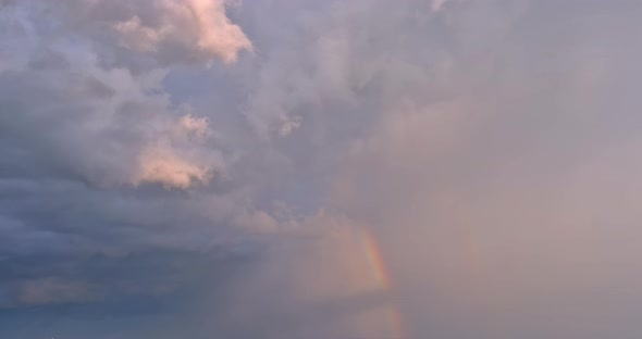 In the Sky of a Severe Thunderstorm a Bright Rainbow is Seen Against a Landscape of Clouds alt