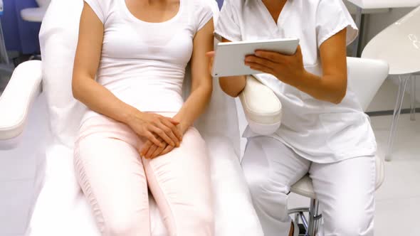 Doctor and female patient discussing on digital tablet alt