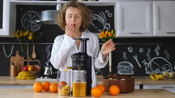 Woman Squeezing Orange Juice In Kitchen In The Morning alt
