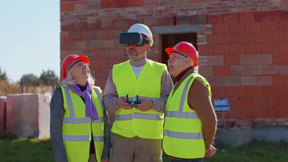 Specialist Worker Fly on Drone on Building Construction Site Showing House to Grandparents Clients alt