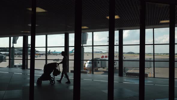 People Walking in the Terminal Overlooking Boarding Plane alt