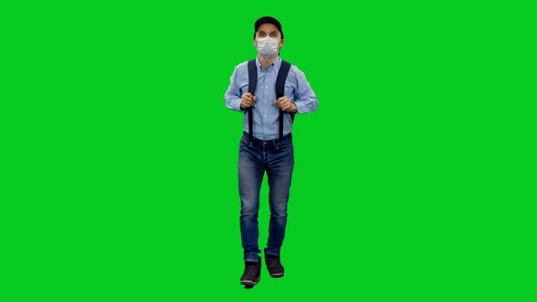 Slender Man in Casual Clothes and Protective Mask Steps with Backpack on Green Screen
